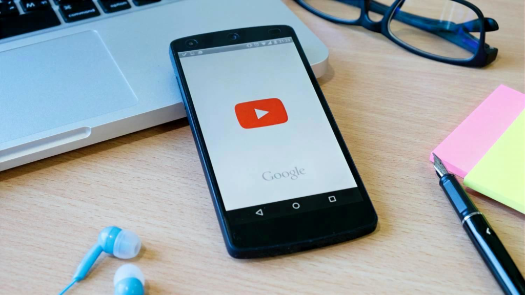 Додаток YouTube на смартфоні поруч із ноутбуком